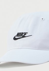 Λευκή καπέλο Nike με καμπυλωτό γείσο, που φέρει μαύρο κεντημένο λογότυπο μπροστά. Κατασκευασμένη από υφασμάτινο ύφασμα με οπές αερισμού.