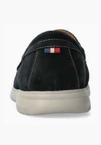 Schwarzer Wildlederschuh mit flacher Sohle, verziert mit weißen Nähten und einem kleinen rot-weiß-blauen Flaggenakzent in der Nähe der Ferse.