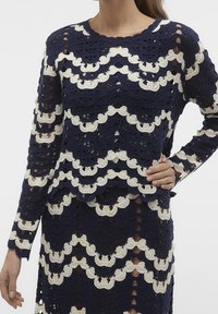 Top all'uncinetto blu navy e crema con motivo a onde, maniche lunghe, scollo rotondo e dettagli a giorno su tutto il tessuto.