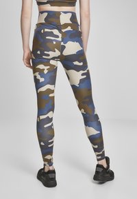 High-waisted leggings featuring a camouflage pattern in blue, brown, and cream colors. Smooth, stretchy fabric and tapered fit.