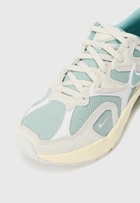 Light teal mesh sneaker with white accents and cream sole. Features textured panels, thick laces, and a prominent brand logo.