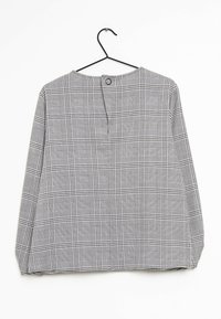 Blusa a scacchi grigia e nera con maniche lunghe, scollatura rotonda e chiusura a bottone sul retro, realizzata in un tessuto leggero.
