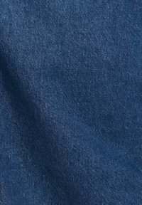 Gros plan d'un tissu en denim bleu montrant la texture et le motif de tissage avec de légères variations d’ombrage.