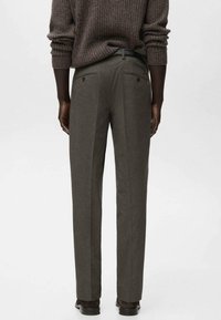 Pantalones de vestir gris oscuro con tela texturizada, corte recto y dos bolsillos traseros. Combinados con un suéter marrón de canalé.