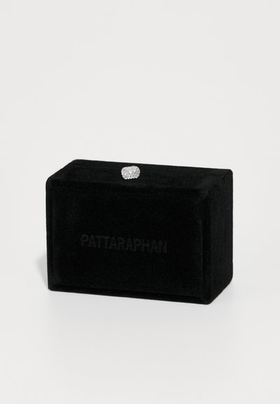 Μαύρη βελούδινη κοσμηματοθήκη με ανάγλυφο το όνομα της μάρκας. Περιέχει ένα δαχτυλίδι με λαμπερή, υφή που παραπέμπει σε πολλούς μικρούς λίθους.