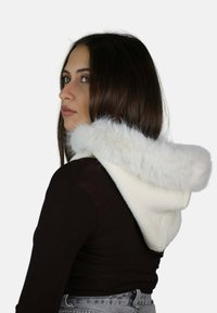 Capucha blanca de punto con un suave ribete de piel sintética, diseñada para ajustarse cerca del cuello. Presenta una textura acanalada y una confección sin costuras.