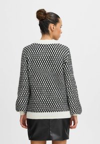 Maglione a righe bianche e nere con una vestibilità ampia, caratterizzato da un motivo a rombi, maniche lunghe e voluminose, e un colletto e orlo bianchi a contrasto.