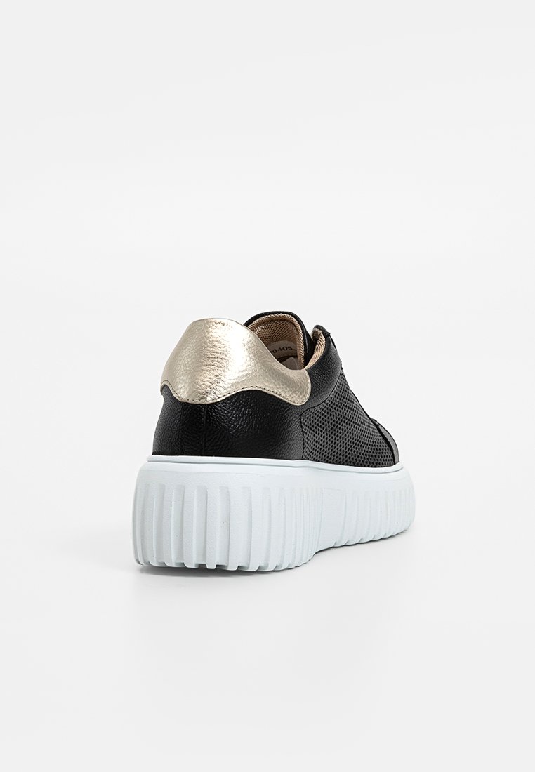 Schwarzer Sneaker aus strukturiertem Leder mit metallic-goldenem Fersenelement und dicker, weißer, gerillter Sohle, von hinten auf weißem Hintergrund gezeigt.
