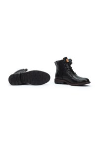 Botas de tobillo de cuero negro con un acabado liso, cordones en la parte delantera, cremallera lateral, suela de goma texturizada y ribete rojo en contraste en la suela.