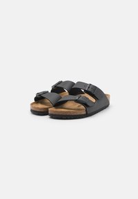 Black sandals with two adjustable straps, cork footbed, and textured rubber sole, featuring buckle hardware detailing.