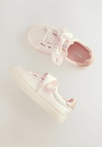 Des baskets roses avec des lacets en satin, en matériau lisse imitant le cuir, une semelle surélevée et de subtils accents texturés sur le talon.