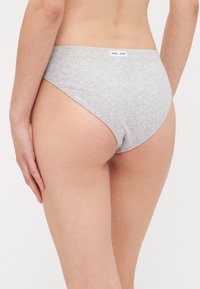 Grå bomull bikini truse med sømløst design, høyt kutt benåpninger og en myk tekstur, med en liten merkevarelabel på midjebåndet.