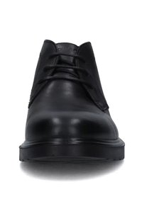 Scarpe di pelle nera con una texture liscia, punta tonda e sei occhielli per i lacci. La suola è piatta e leggermente arrotondata.