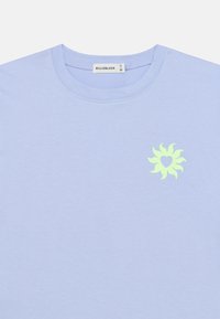 Ανοιχτό μπλε βαμβακερό T-shirt με στρογγυλή λαιμόκοψη. Διαθέτει γραφικό ήλιο σε κίτρινο-πράσινο χρώμα με μια καρδιά στο κέντρο στο αριστερό μέρος του στήθους.