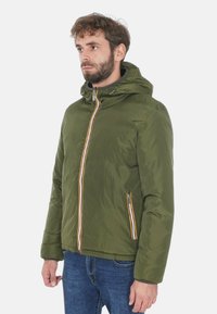 Giacca verde con cappuccio e zip frontale, con una striscia multicolore lungo la zip e tasche laterali. Finitura liscia e imbottita.