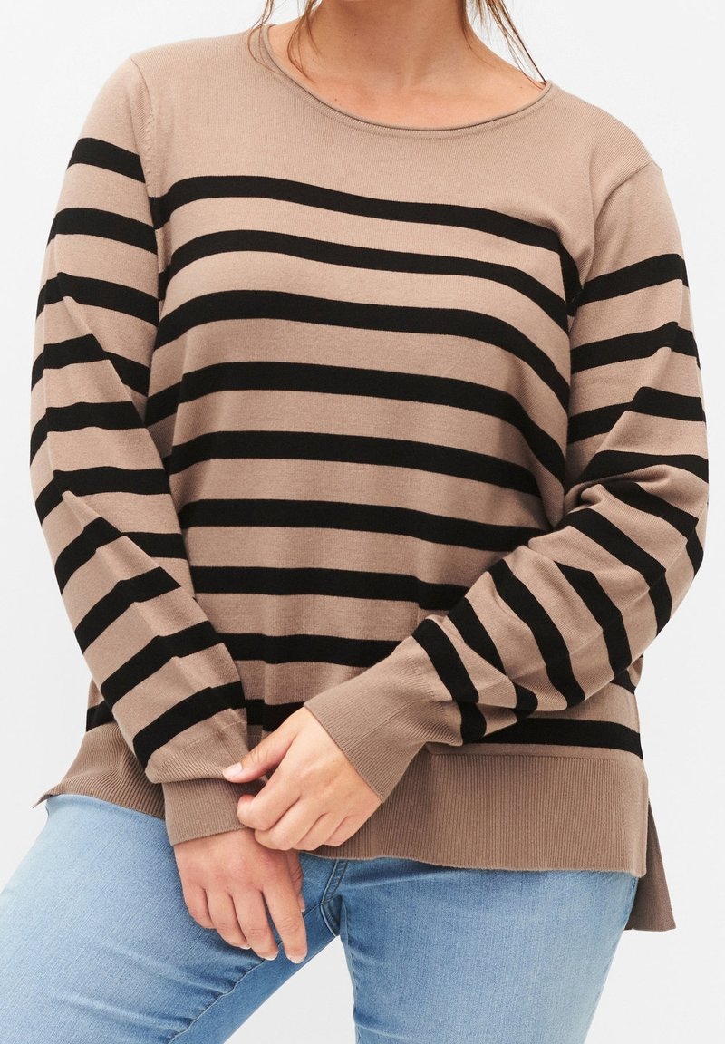 Pull en tricot beige avec des rayures horizontales noires, encolure ronde et manches longues avec des poignets côtelés. Fentes latérales au niveau de l'ourlet.