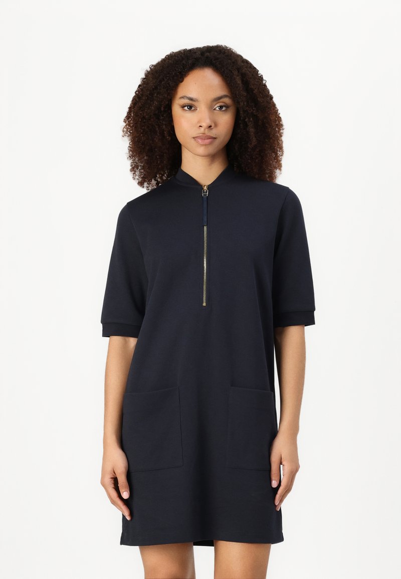 Millitärblaues kurzärmeliges Kleid mit Reißverschlusskragen, ausgestattet mit zwei vorderen Taschen, aus weichem Stoff mit lockerer Passform.