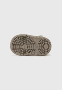 Semelle de sneaker gris clair avec des motifs circulaires texturés et des rainures. Présente un logo au centre, conçu pour l'adhérence et la durabilité.