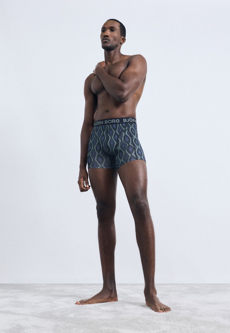 Idrettsmann som står barbeint på teppe, iført mønstrede boxershorts med "BJÖRN BORG" midjebånd, hånden hvilende på motsatt skulder.