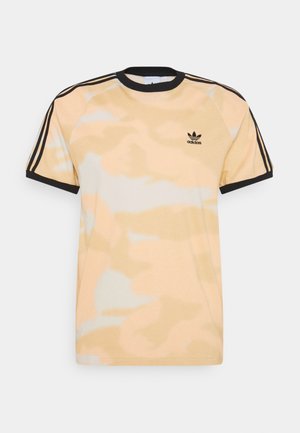 Jasnobeżowa i biała koszulka Adidas tie-dye z czarnym wykończeniem i czarnym detalem w postaci trzech pasków na ramionach i rękawach, małe logo na piersi.