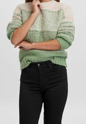 Gebreide trui in groen en crème met een gestructureerd, gestreept patroon. Voorzien van een ronde halslijn en geribbelde manchetten. Gecombineerd met zwarte jeans.