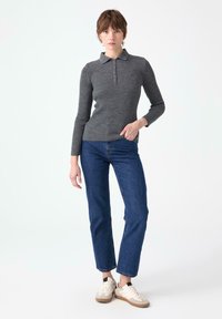 Hallgrå ribakudumiga polo särgiga, millel on krae ja nööbiplikaat, koos siniste sirgete pükstega ja kreemjate spordijalatsitega. Ühtlane tekstuur kogu ulatuses.