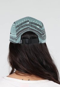Casquette bleue à motifs avec des rayures noires et des designs géométriques. Elle possède une sangle ajustable à l'arrière et une texture de tissu douce.
