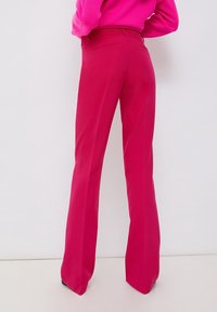 Rozšířené kalhoty v jasně růžové barvě, vyrobené z hladkého materiálu. Mají zadní kapsy a přiléhavý pas. Čisté linie zdůrazňují siluetu.