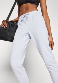 Hellblaue Sweatpants aus Baumwollmischung mit einem Kordelzugbund und Seitentaschen. Mit einem weißen Puma-Logo auf dem linken Oberschenkel.