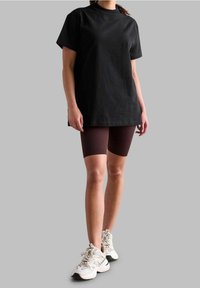 Sort bomulds t-shirt med rund halsudskæring og korte ærmer, parret med ribbede burgundy cykelshorts og kraftige hvide sneakers.