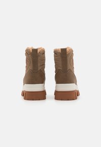Brune mid-top støvler med strukturert lær og polstret overdel. Har en lys såle og en pelsfôr øverst.