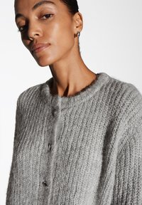 Cardigan grigio con bottoni, tessuto a maglia testurizzato, scollo rotondo e cinque bottoni. Tessuto liscio e morbido con una vestibilità casual.