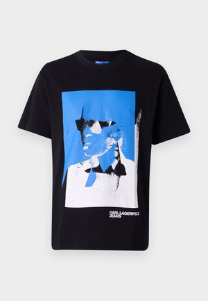 T-shirt en coton noir présentant un graphique audacieux en bleu et blanc d'un visage avec des lunettes de soleil. "KARL LAGERFELD JEANS" imprimé en bas.