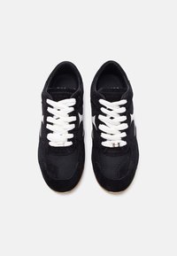 Ζευγάρι μαύρα αθλητικά παπούτσια από σουέτ και δίχτυ, με λευκά κορδόνια και λευκή πλευρική λωρίδα, φωτογραφισμένα από πάνω σε λευκό φόντο.