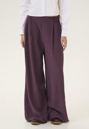 Brede broek in diep paars, gemaakt van soepel stof. Heeft plooien op de taille, zijzakken en een relaxte pasvorm.