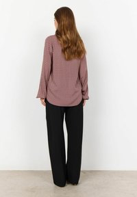Maroon patterned blouse with long sleeves, textured fabric, and relaxed fit, paired with black wide-leg trousers.