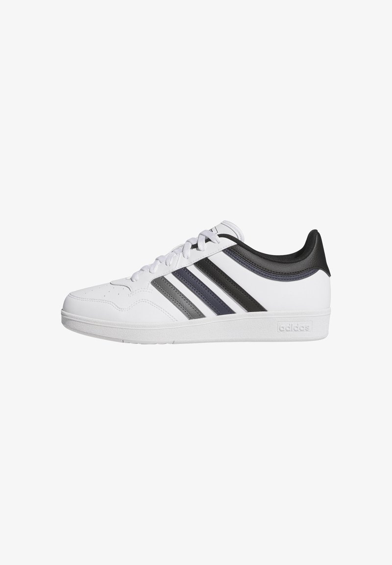 Sneaker bassa bianca con strisce nere, blu navy e grigie, tab di tallone nero e suola bianca con logo in rilievo sul lato.