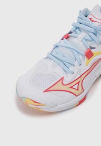 Hvide atletiske sko med lyseblå snørebånd, gule og røde accenter, mesh-overdel og en farverig, mønstret sål. Har Mizuno-branding.