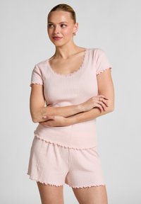 Lichtroze geribbeld pyjama set met korte mouwen en shorts, met een gegolfde rand en een structuurstof. Verfraaid met subtiele details.
