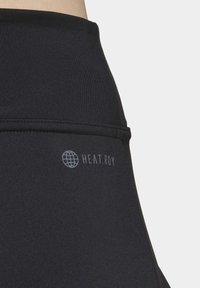 Sorte atletiske leggings med en høj talje, glat stoftekstur og "HEAT.RDY"-logo i en kontrasterende lyseblå farve nær hoften.