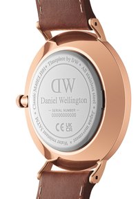 Orologio Daniel Wellington con fondo in acciaio inossidabile, cassa in oro rosa e cinturino in pelle marrone con cuciture bianche. Numero di serie visibile.