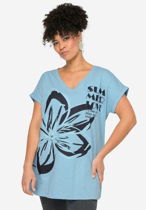 T-shirt bleu clair à col en V avec un grand graphique floral noir, impression texte et accents en perles, doté de manches courtes et d'une coupe décontractée.