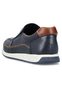Zapatos de cuero azul marino con un detalle de cuero marrón, que presentan costuras decorativas y una suela de goma blanca, diseñados para ofrecer comodidad y estilo.