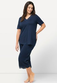 Ensemble de pyjama en coton bleu marine comprenant un haut à manches courtes avec un col en dentelle et des accents en dentelle, ainsi que des pantalons courts avec une bordure en dentelle au bas.