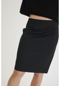 Svart knälång blyertskjol med en mjuk textur, som har framfickor och en figursydd design som formar sig efter kroppen.