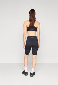 Schwarzes Sportset mit einem nahtlosen Bralette und hochgeschnittenen Shorts mit strukturierten Akzenten und figurbetontem Design.