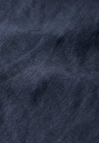 Tessuto di un blu navy scuro con una superficie texturizzata, che mostra sottili motivi intrecciati. Il materiale ha un aspetto morbido e leggermente stropicciato.