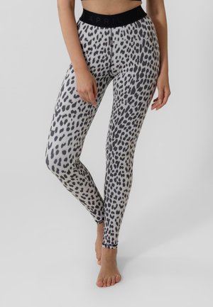 Leopard-Print Leggings in Schwarz und Weiß, mit einem schwarzen elastischen Bund, der den Markennamen "APRIL" trägt, und einer figurbetonten Passform.