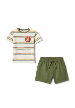 Kurzärmliges cremefarbenes Hemd mit mehrfarbigen Streifen und Löwen-Patch, kombiniert mit olivgrünen Shorts mit Fronttaschen und Kordelzug am Bund.