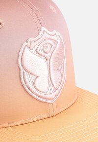 Cap with a gradient from light pink to orange, featuring a textured embroidered logo of a butterfly and eye. Smooth fabric finish.